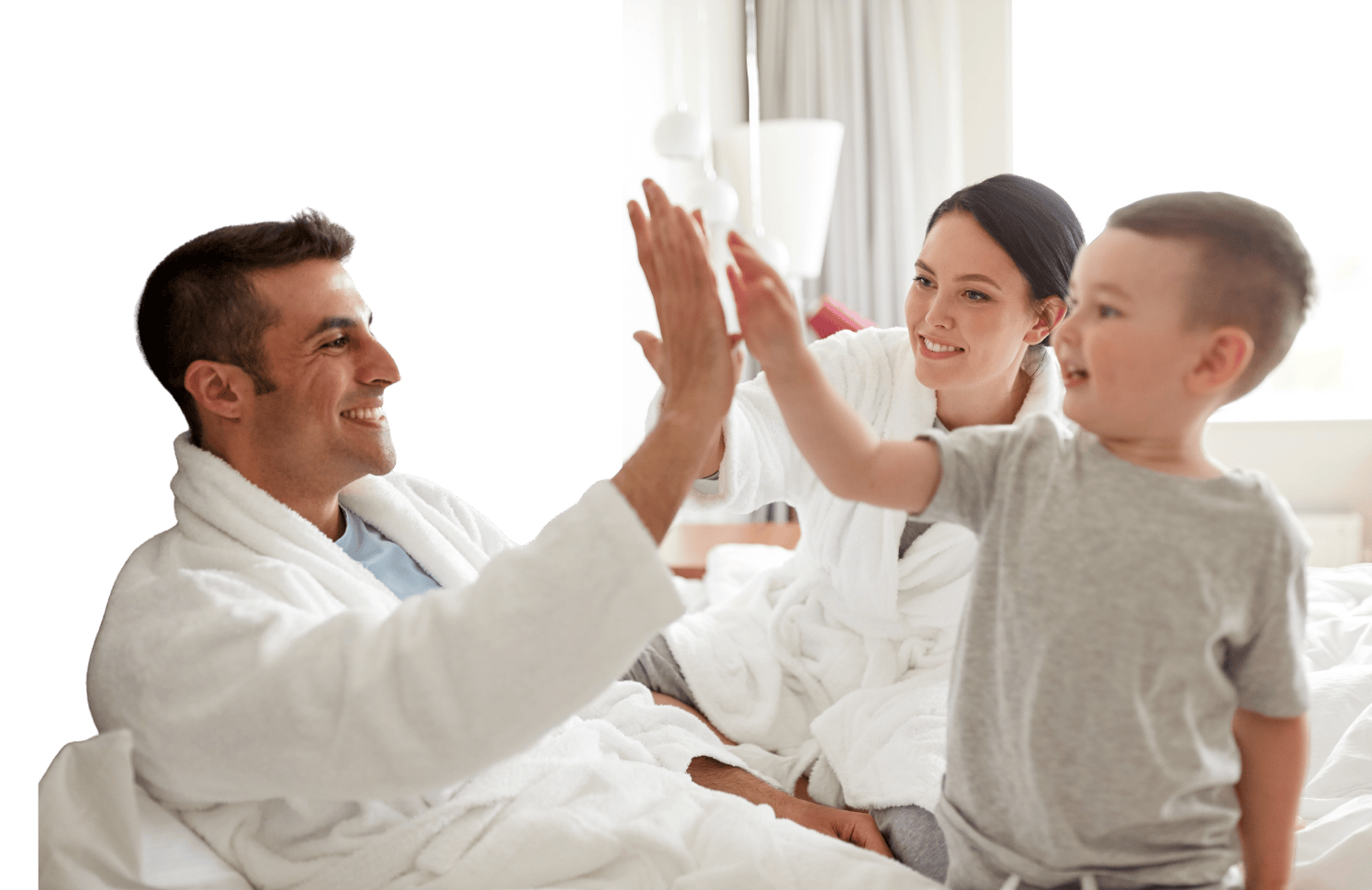 A family sharing a high five on a made bed