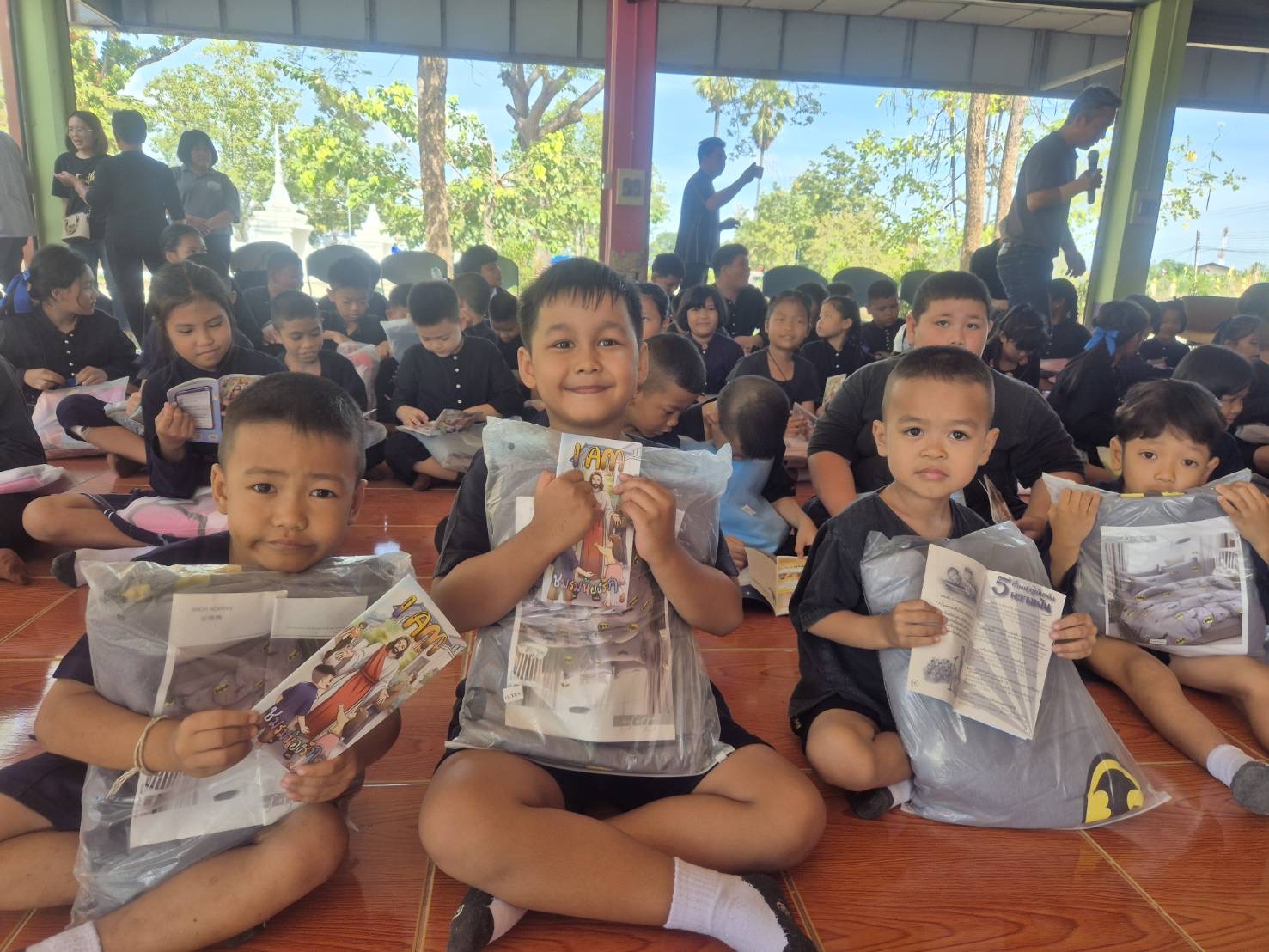 Children at a school in Thailand holding donated bedding sets